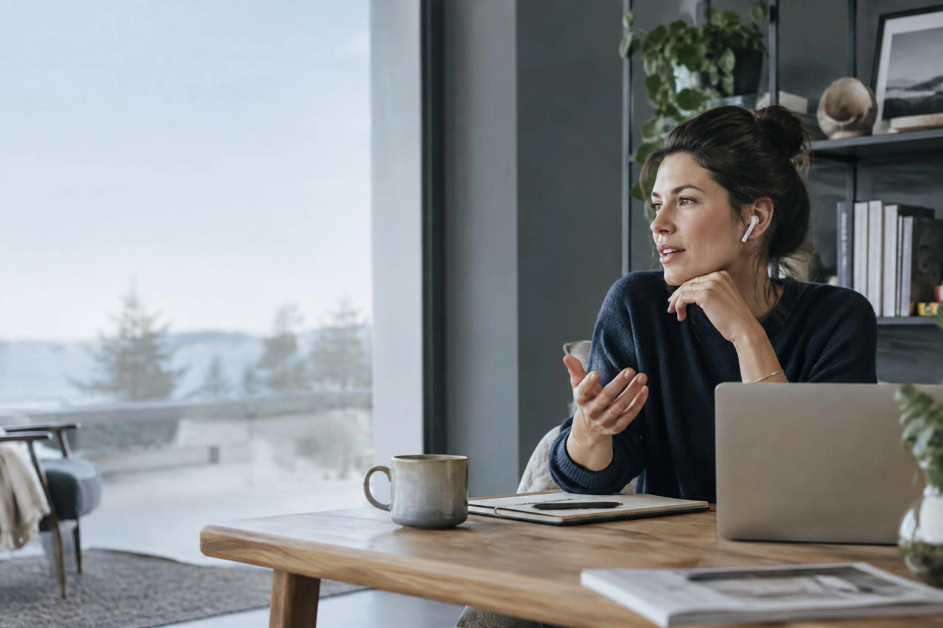 A professional speaking through a wireless earbud in a home workspace